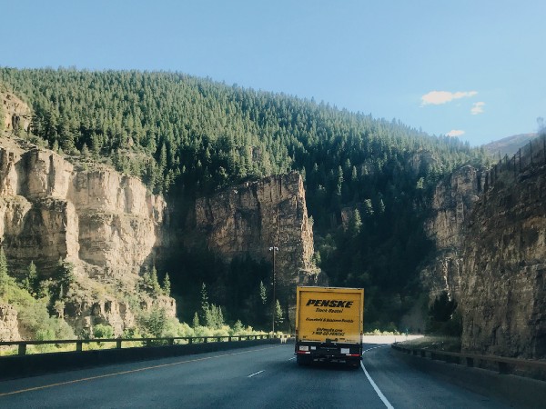 yellow Penske moving truck on a road through a canyon