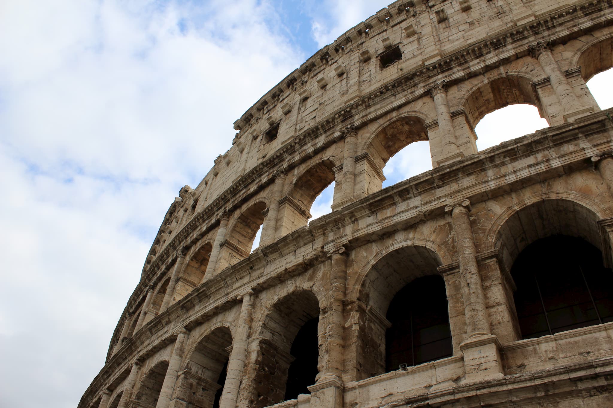 Curved outside wall of the ancient Colosseum sports arena with multiple levels of arches