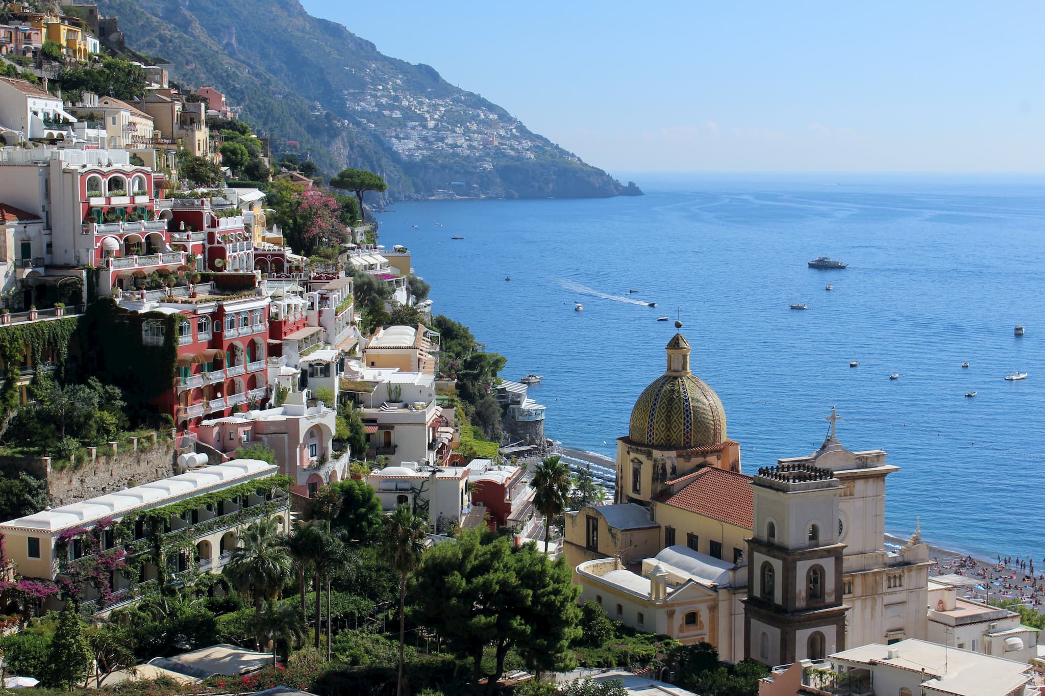 Buildings built into a coastal hillside with a large, tiled church dome below