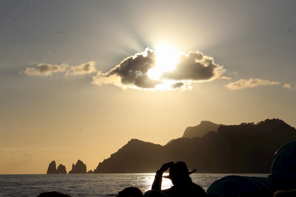 Silhouette of an island with the sun shining through a cloud.