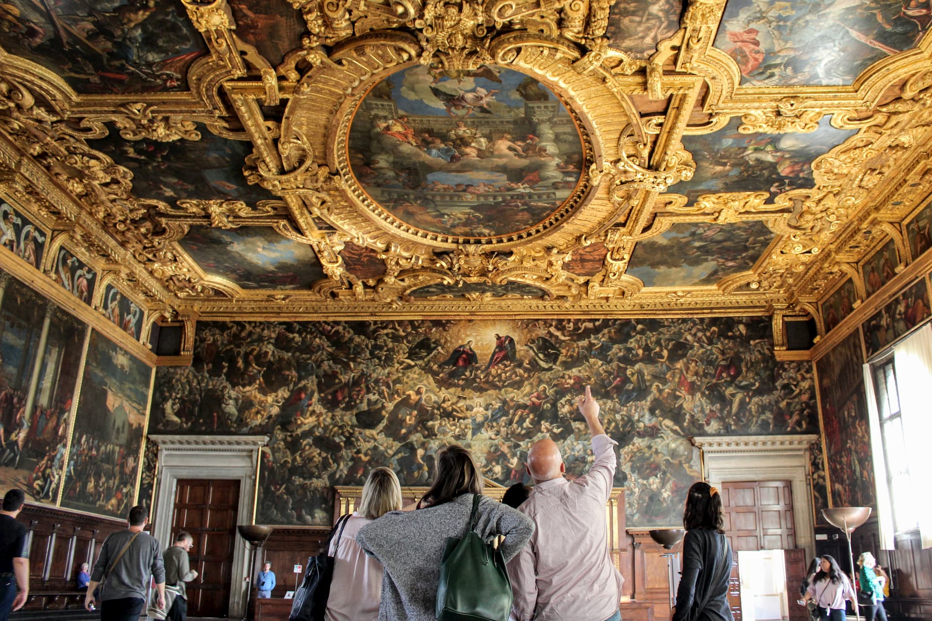 People looking up at paintings and gold leaf moldings