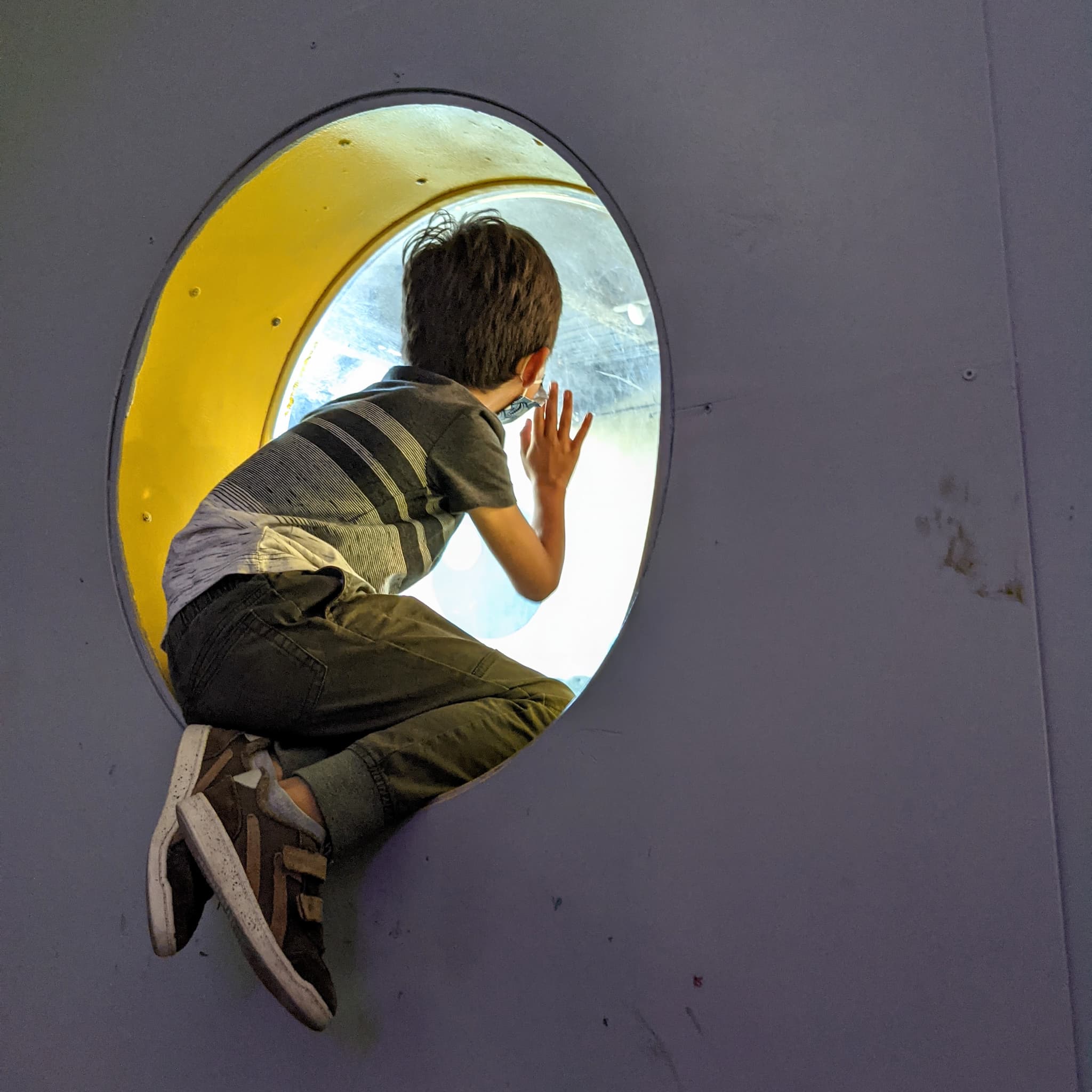 Boy looking out of a round window.