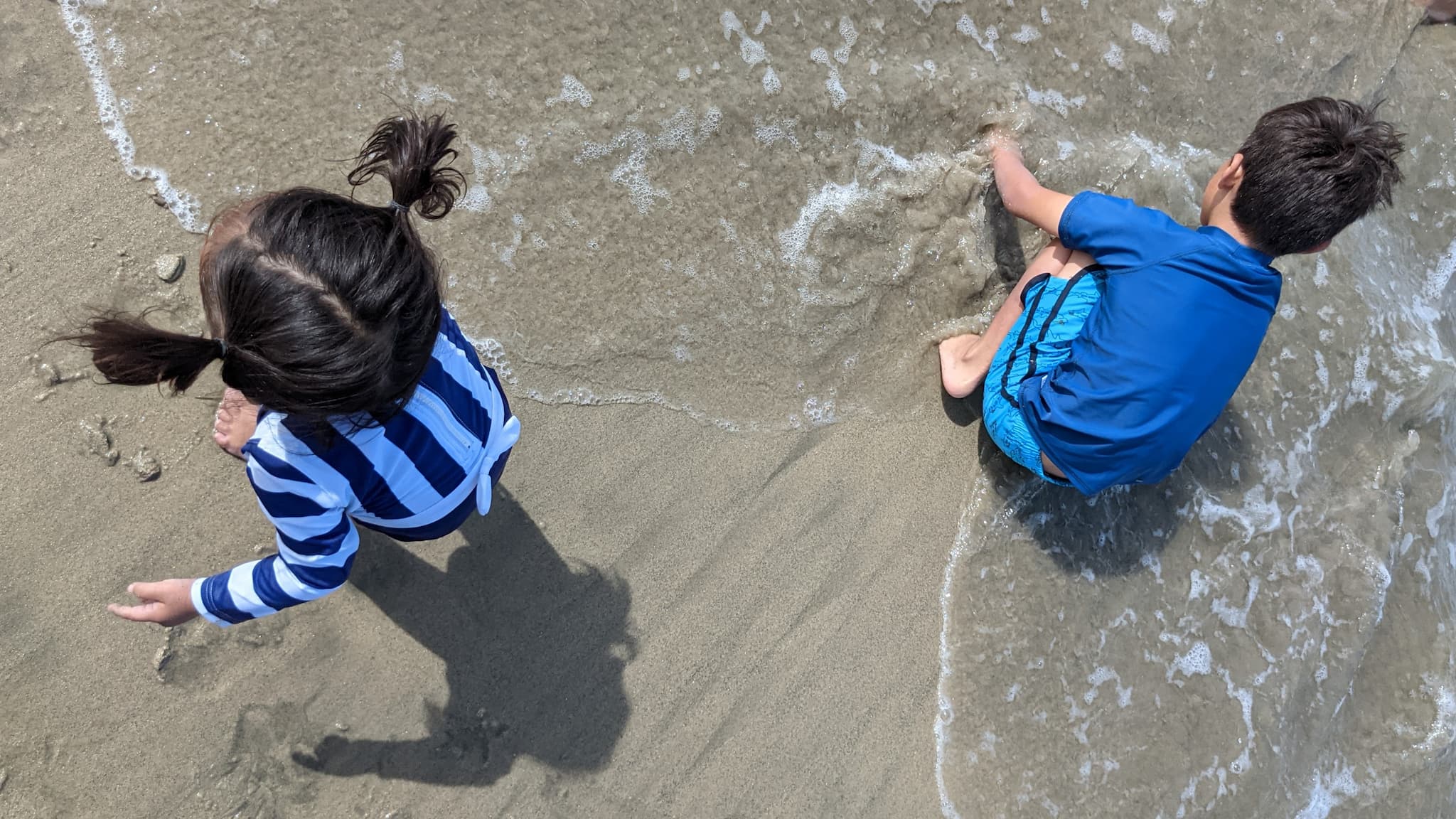 Two children, a boy and a girl playing on a sandy beach