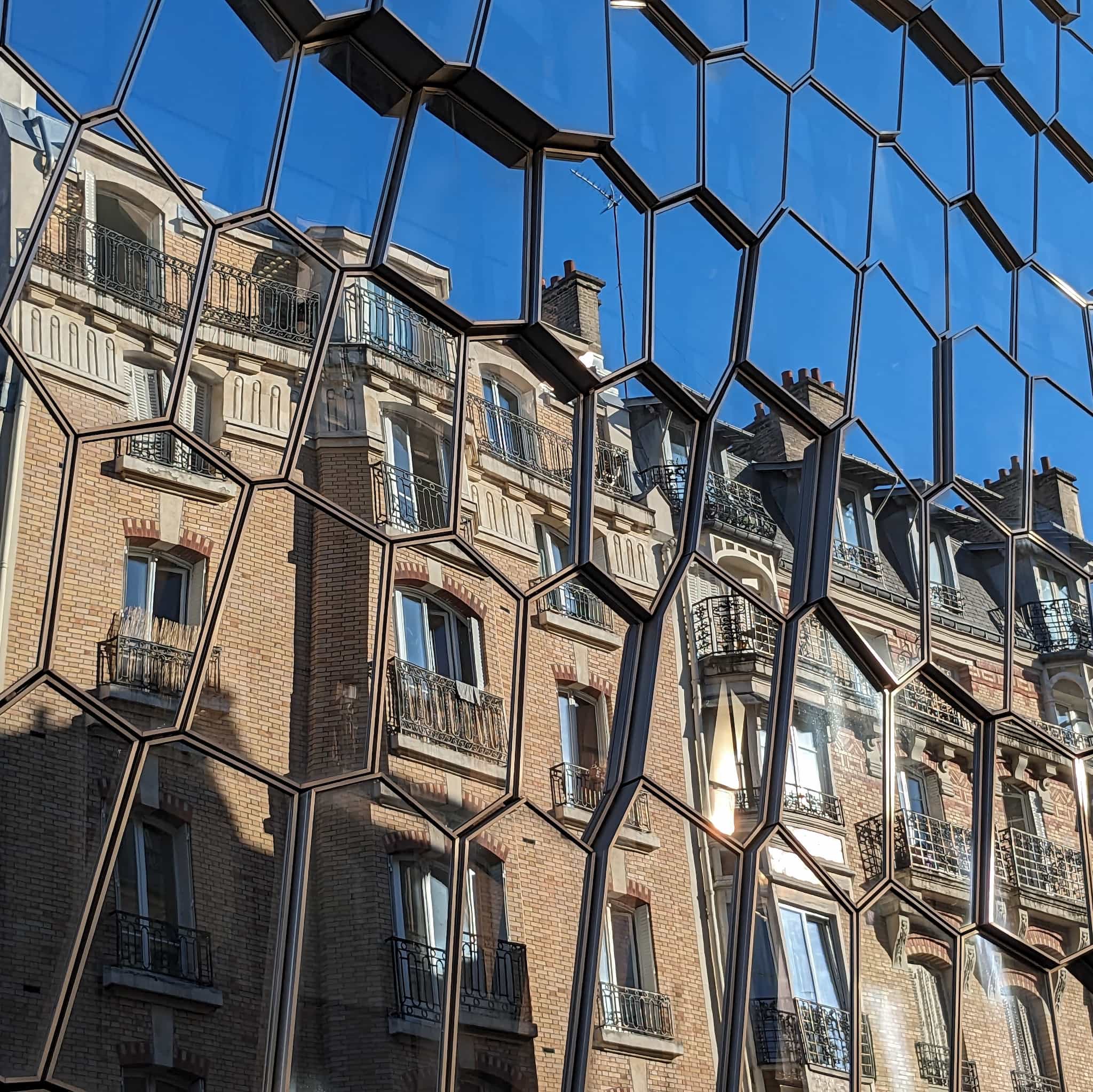 Reflection of a brick building in irregular hexagon shaped glass panels.