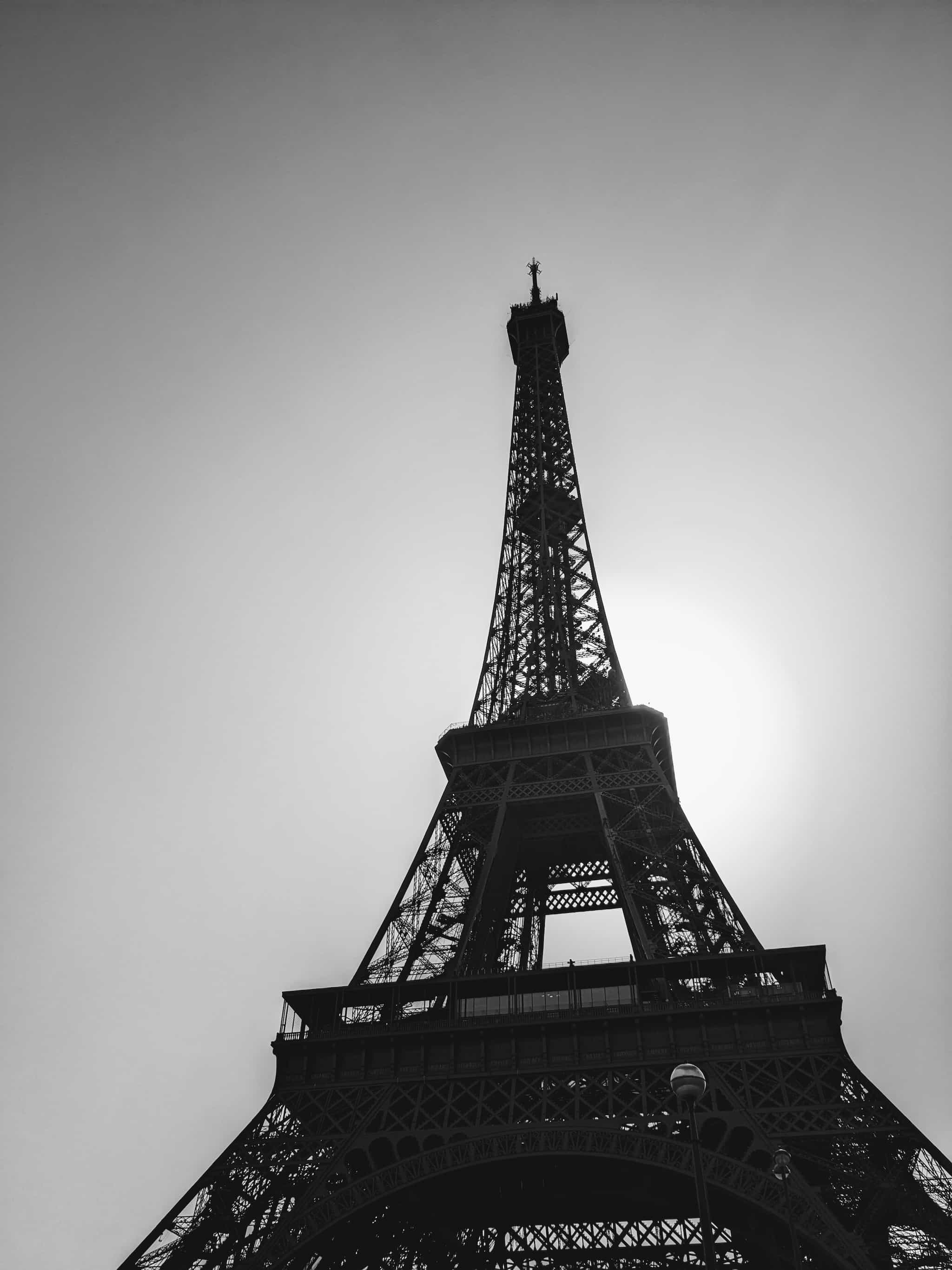 Black and white silhouette of the Eiffel tower from below. 