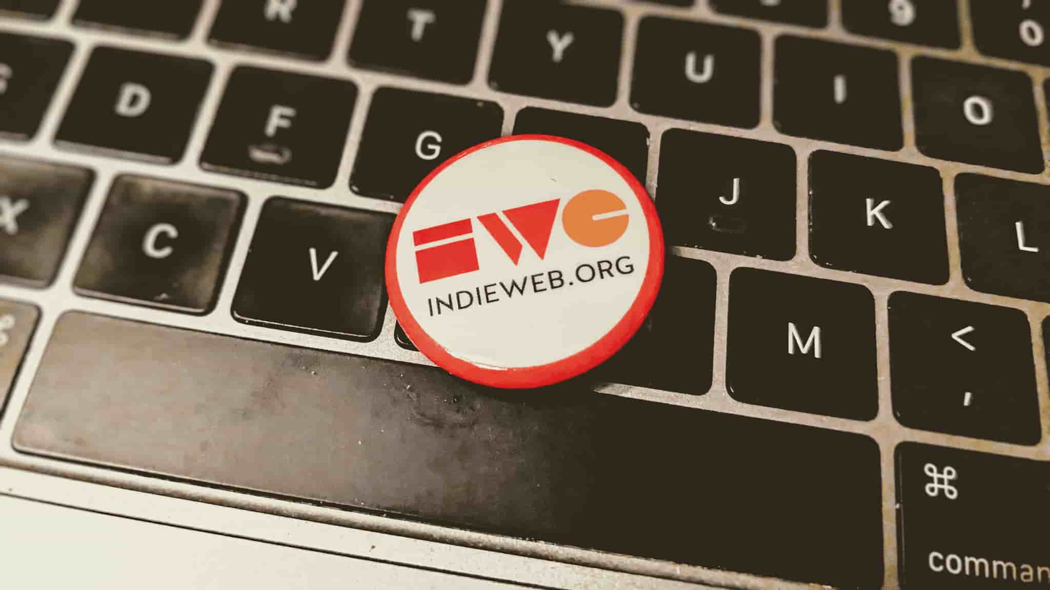 A closeup of a IndieWebCamp button resting on a computer keyboard.