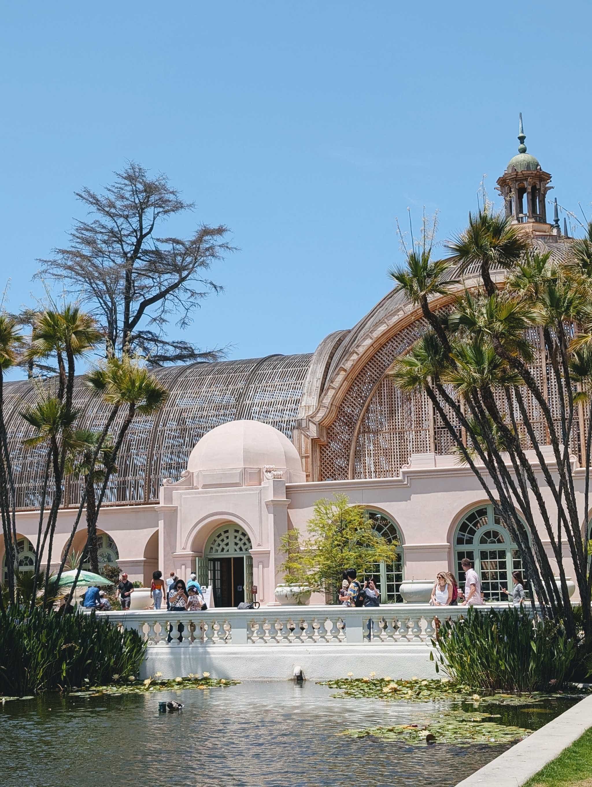 exterior of the shade structure with a pool in front with lilly pads and palm trees.