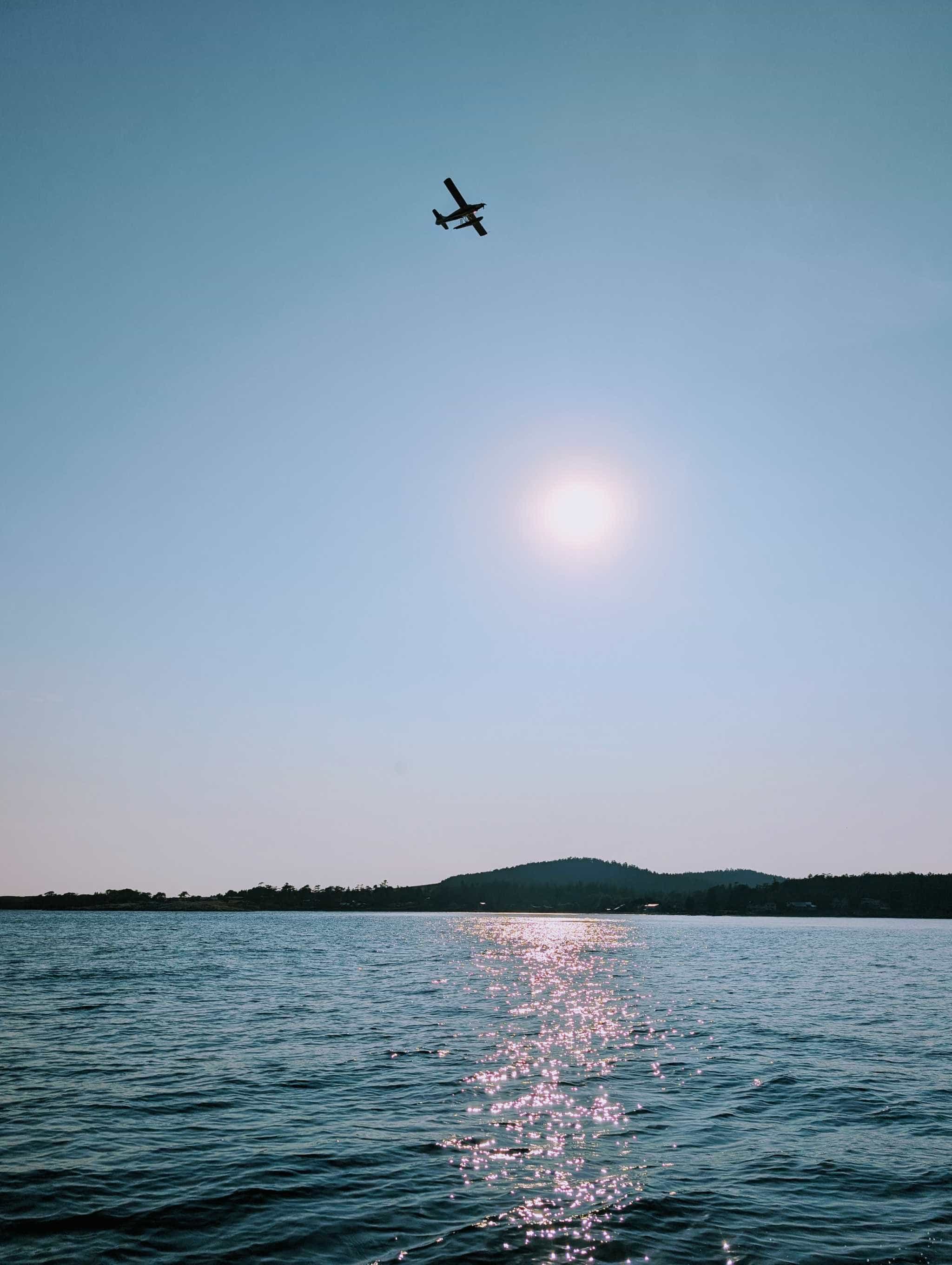 view of a plane flying over water with some land visible but blue overwhelms the image.