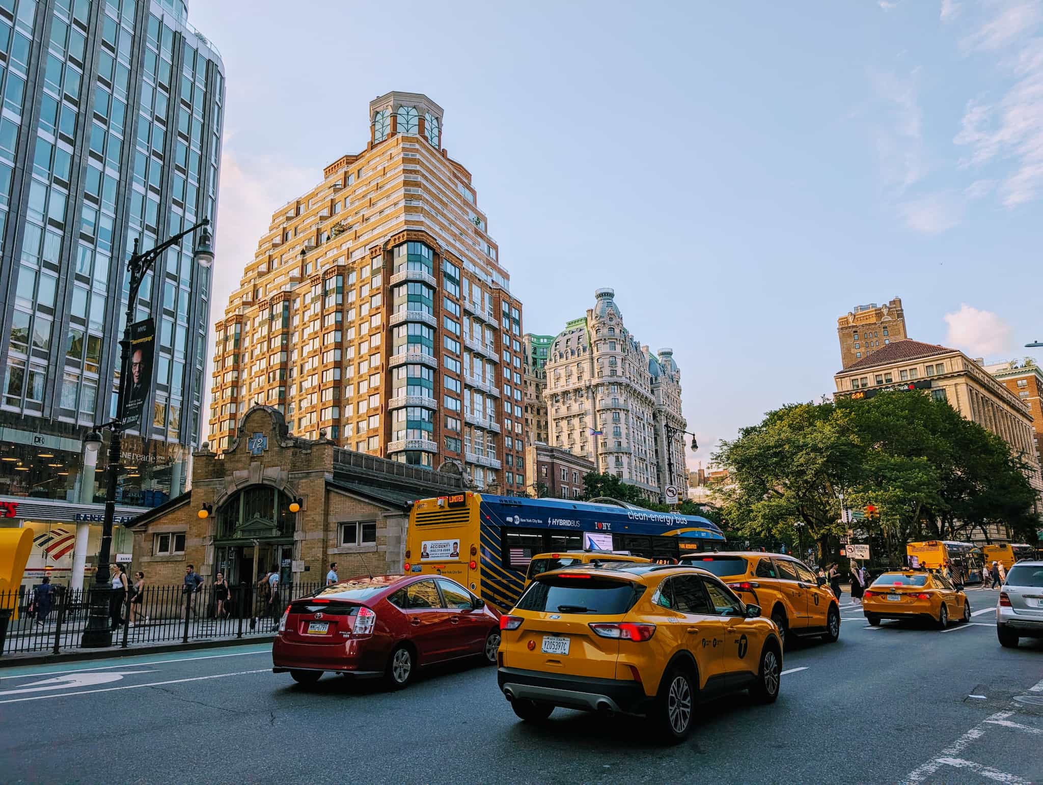 Yellow taxi cabs driving through a city street with a mix of architectural styles.