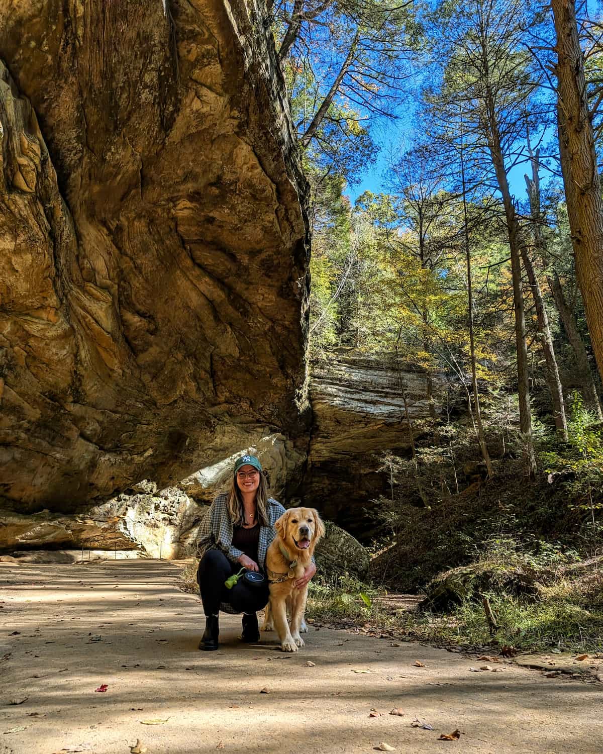 A woman and dog stand inside a large open cavern.