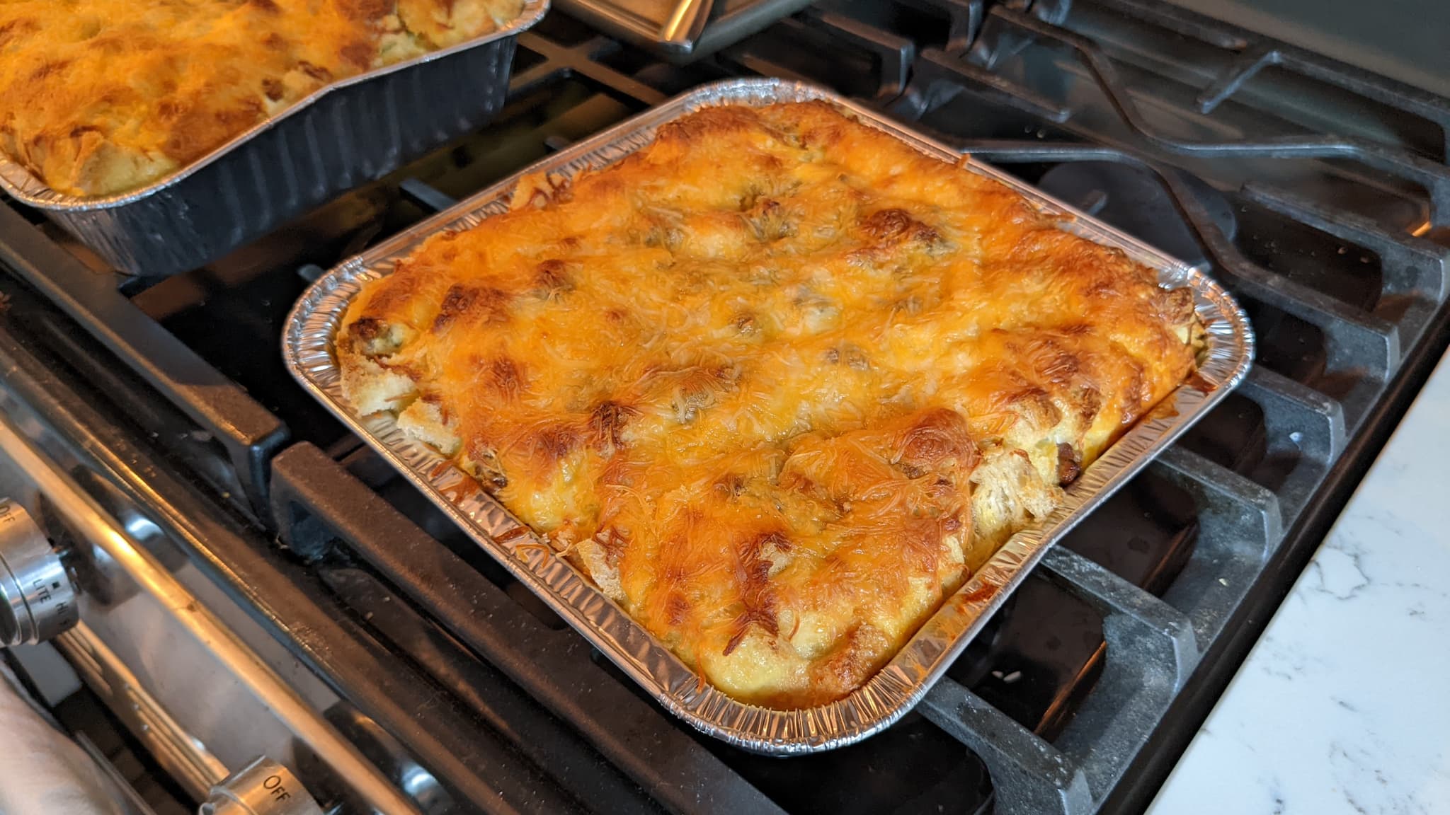 aluminum pan with cheese baked on top of a yellow mixture.