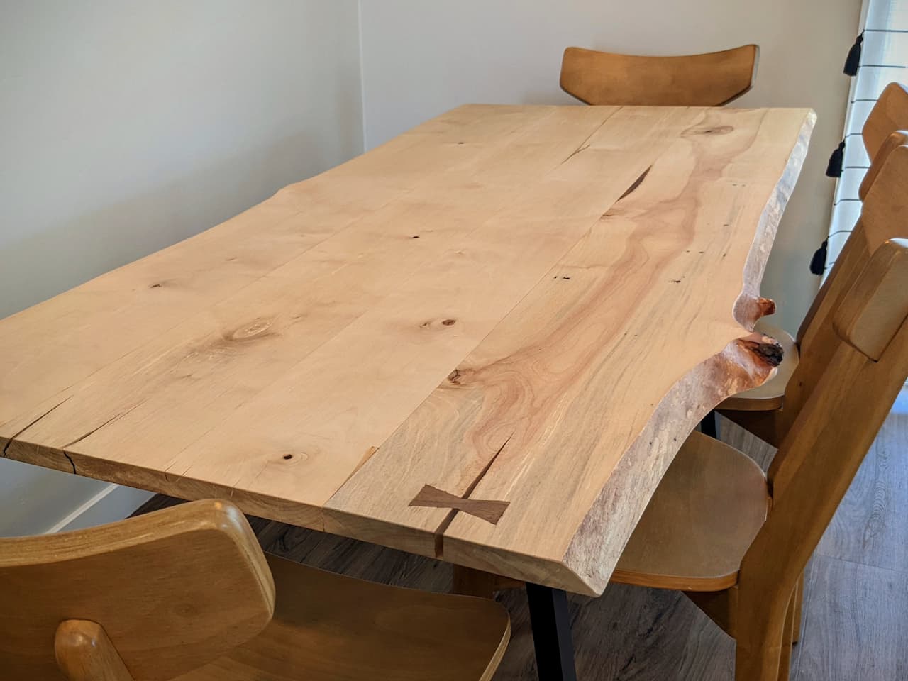 surface of wood table showing inlay, epoxy, and wood knot details