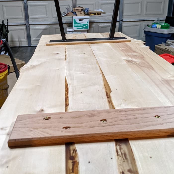 Boards screwed to the bottom of a table. One rectangular table leg mounted to a board.