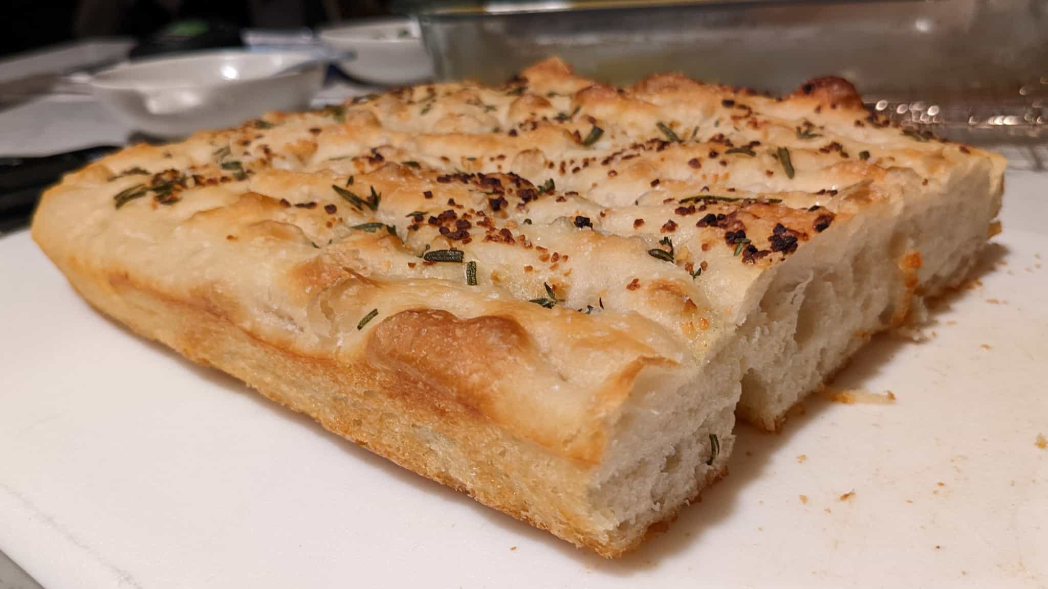 Loaf of flat focaccia bread topped with garlic and rosemary