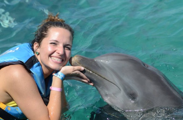 woman in life vest being "kissed" by a dolphin