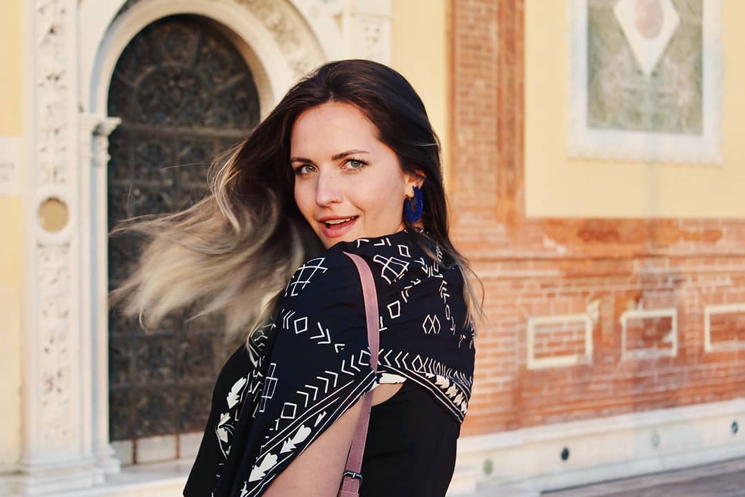 A woman turning her head and smiling dramatically at the camera while her hair whips around behind her.