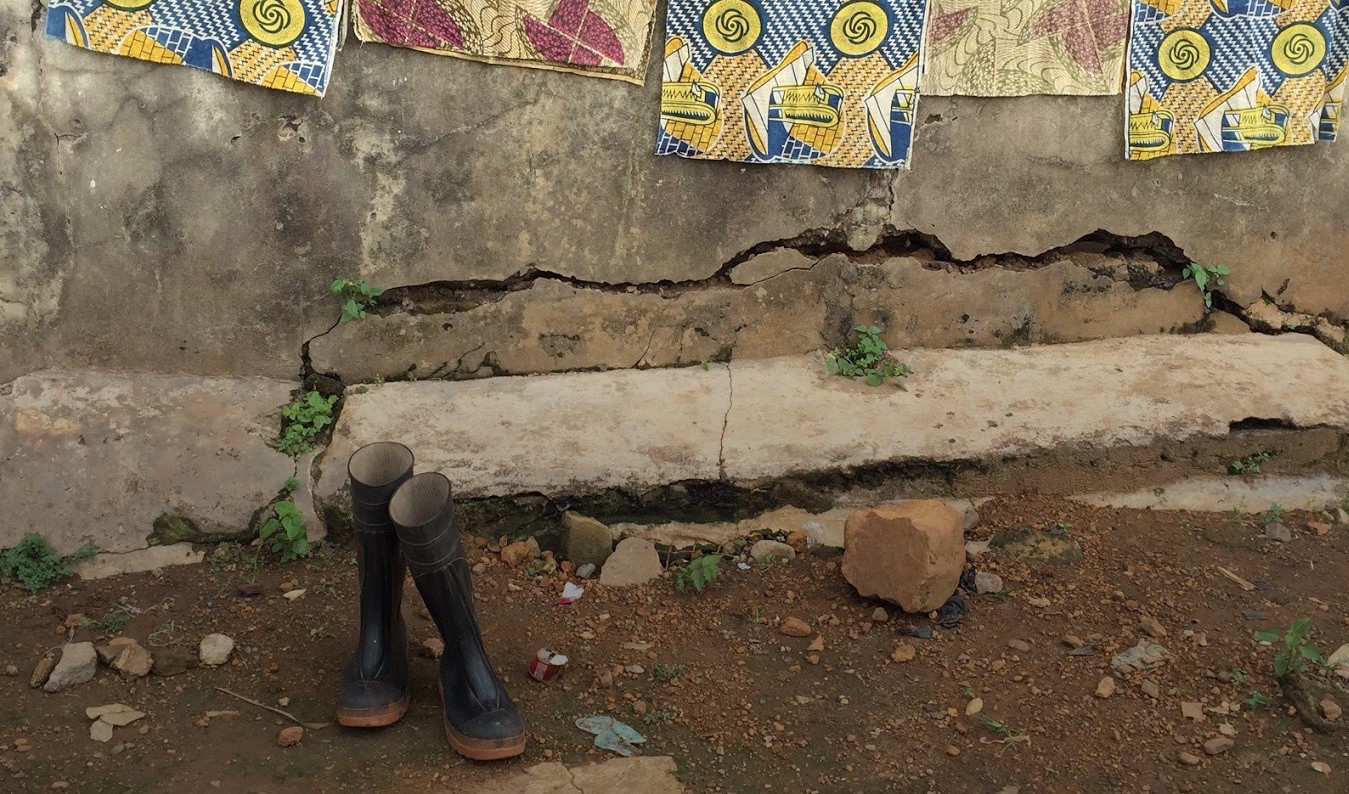 outside of a plaster wall with colorful cloth hanging and a pair of rain boots