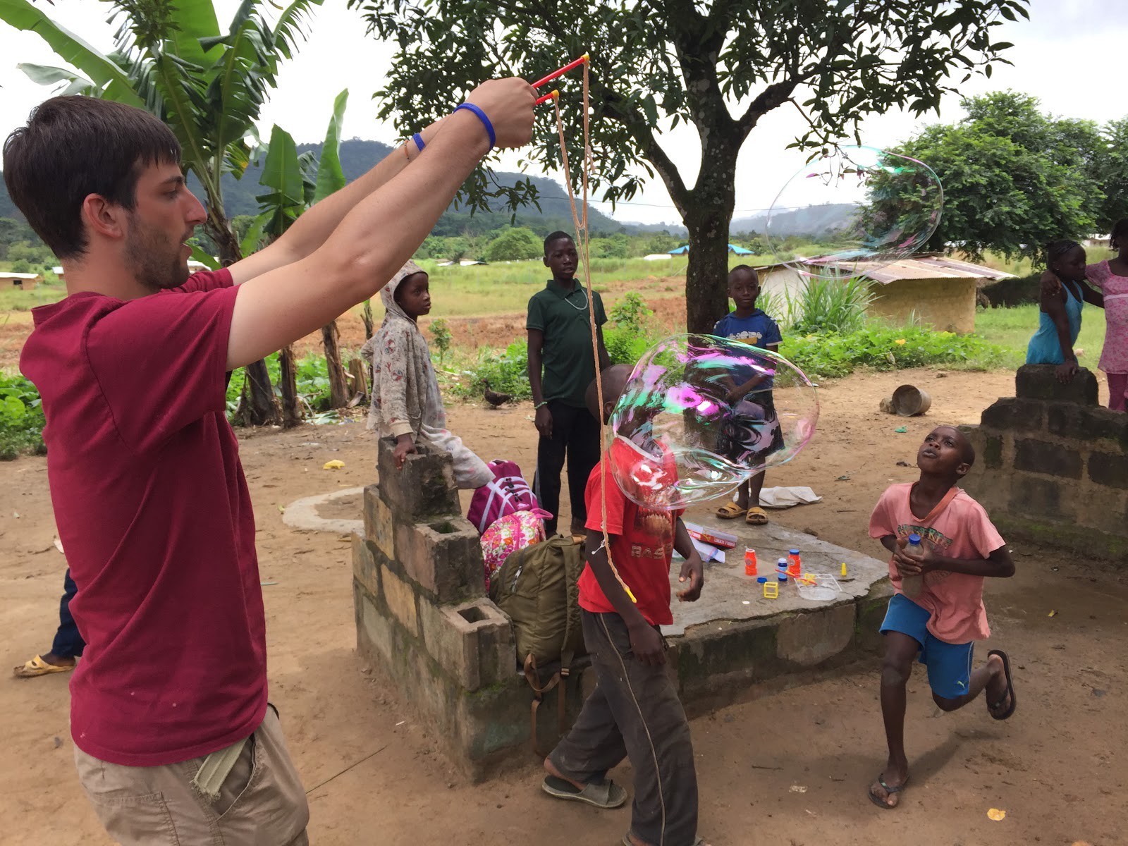 white maile holding two sticks with dangling strings making gian bubbles outdoors