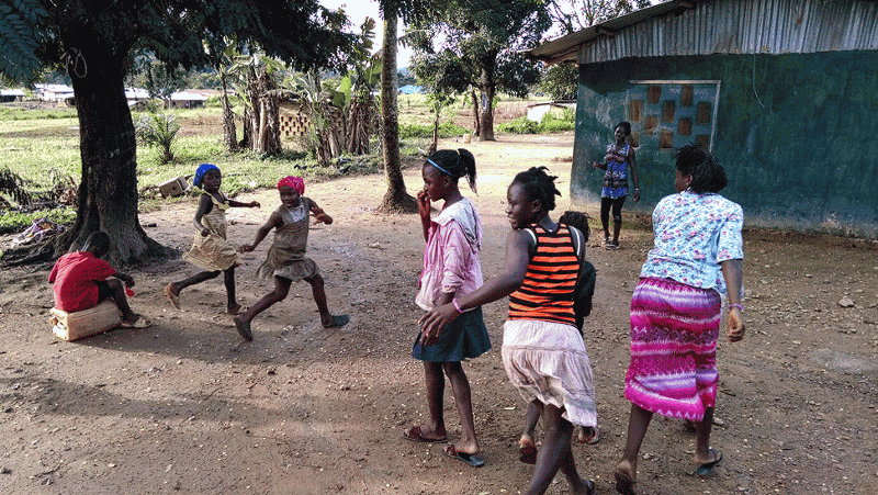 african girls playing with a ball in a small yard