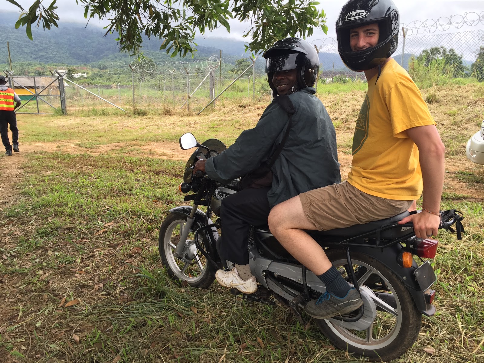 African man on seat of motorcycle with a white man on the back ready to drive off