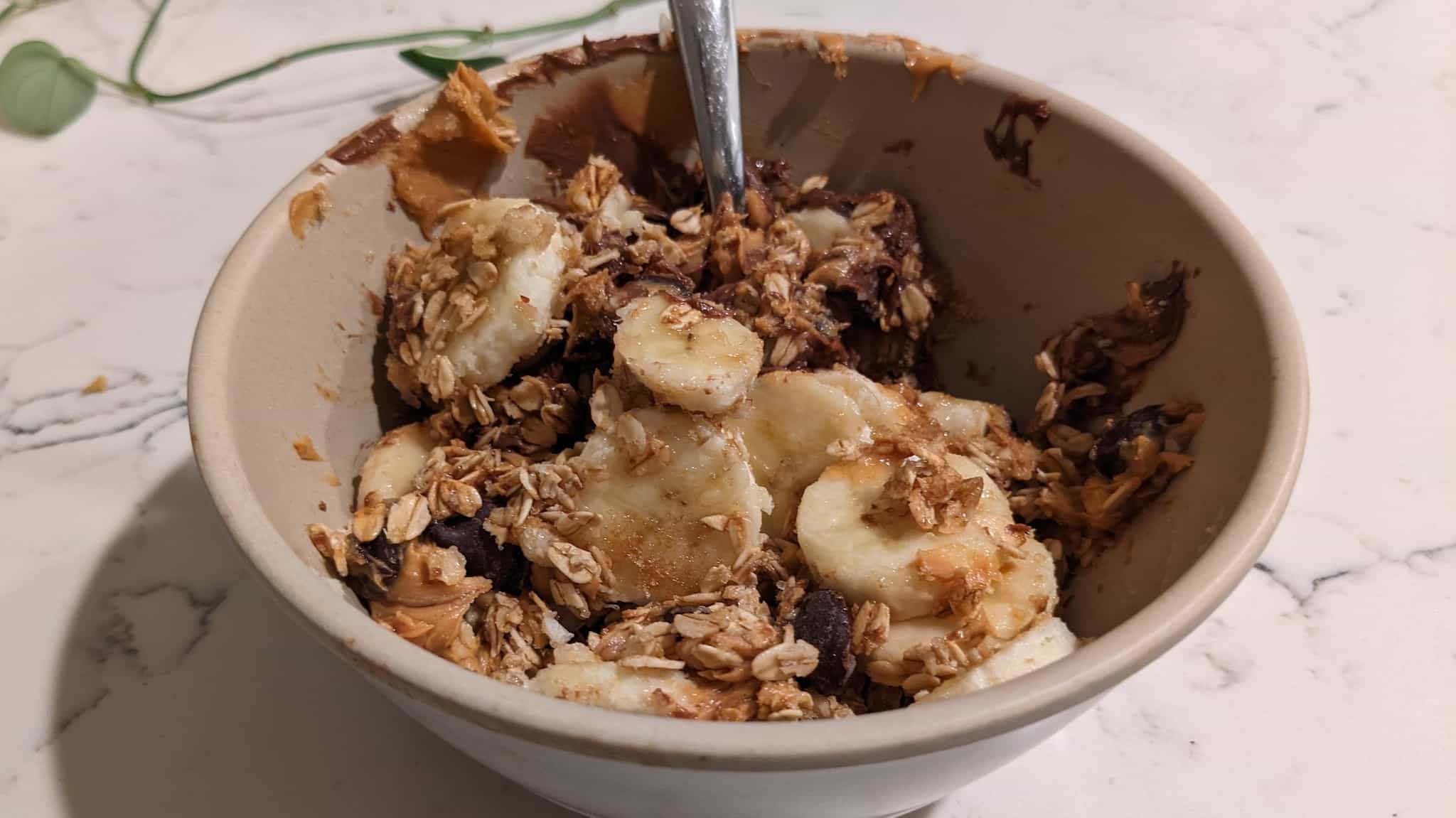 Bowl with banana slices topped with granola, peanut butter, and chocolate chips.