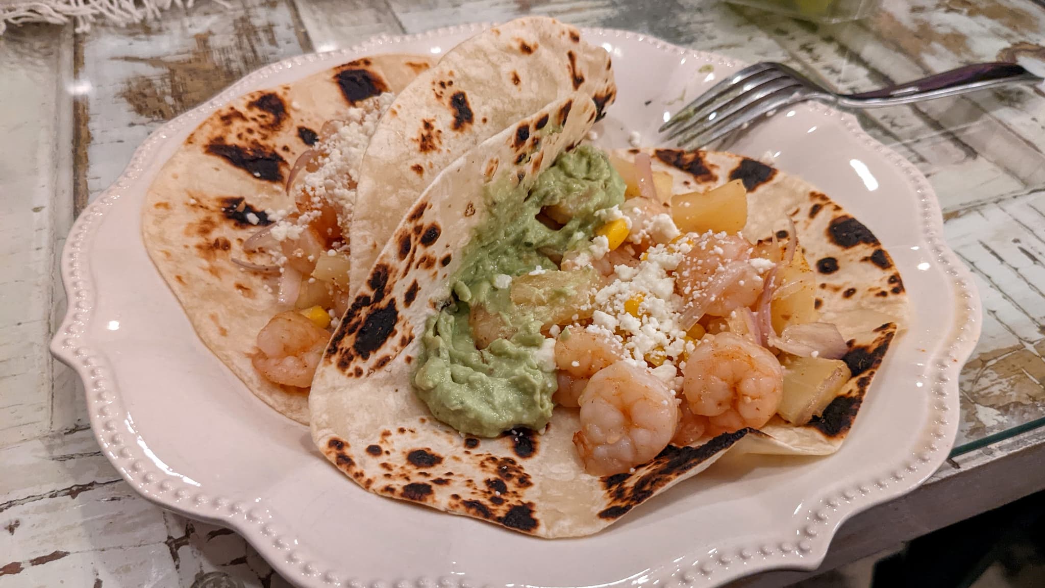 two tortillas filled with shimp, pinapple, and guacamole