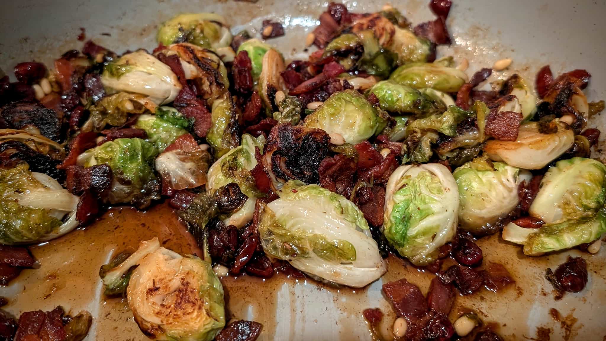 Pan of halved Brussels sprouts with bacon in a thick syrup