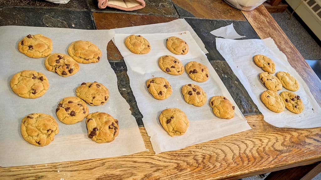 Chocolate chip cookies resting on parchment on a table.