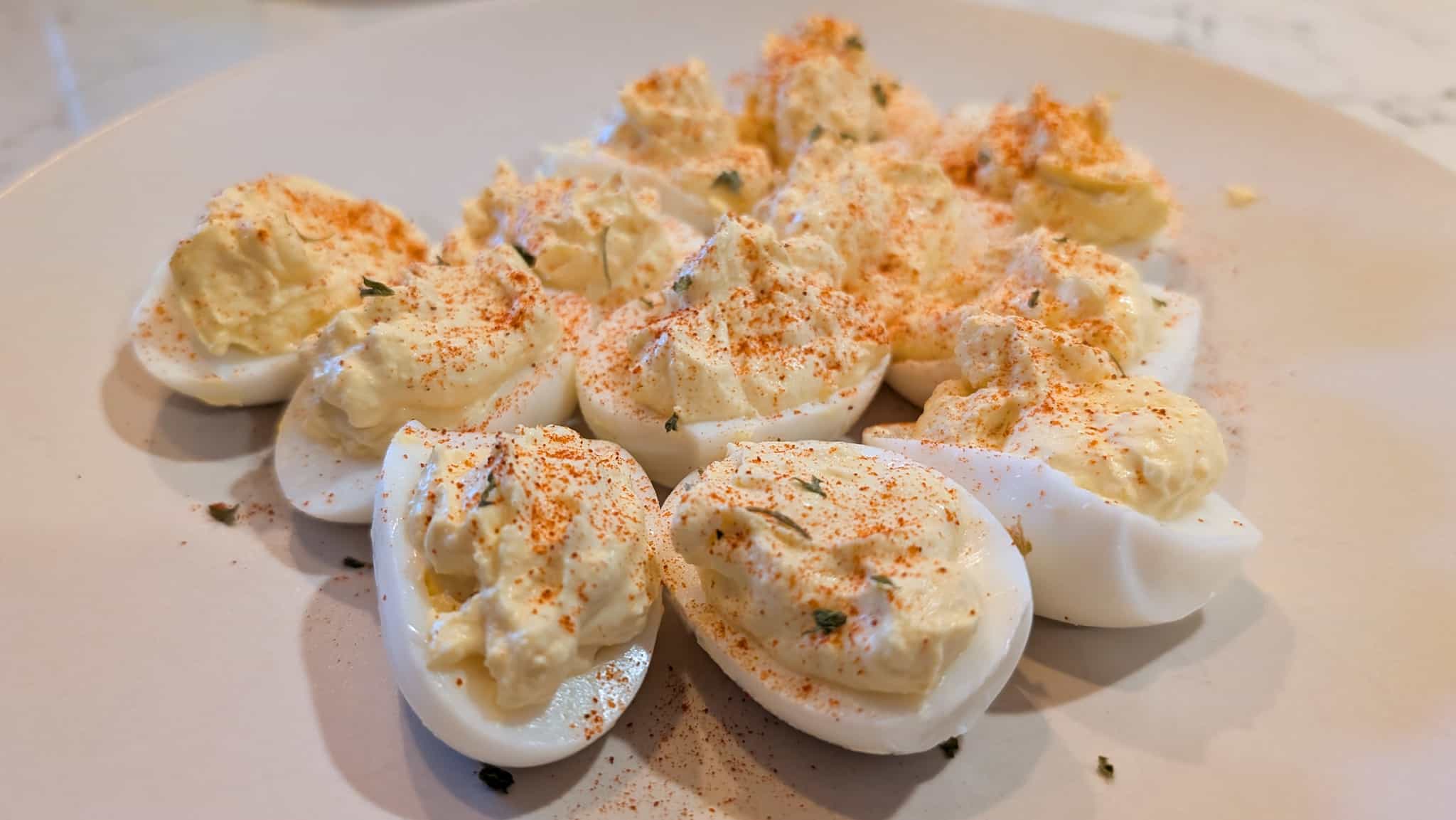 A plate of deviled eggs garnished with paprika and parsley.