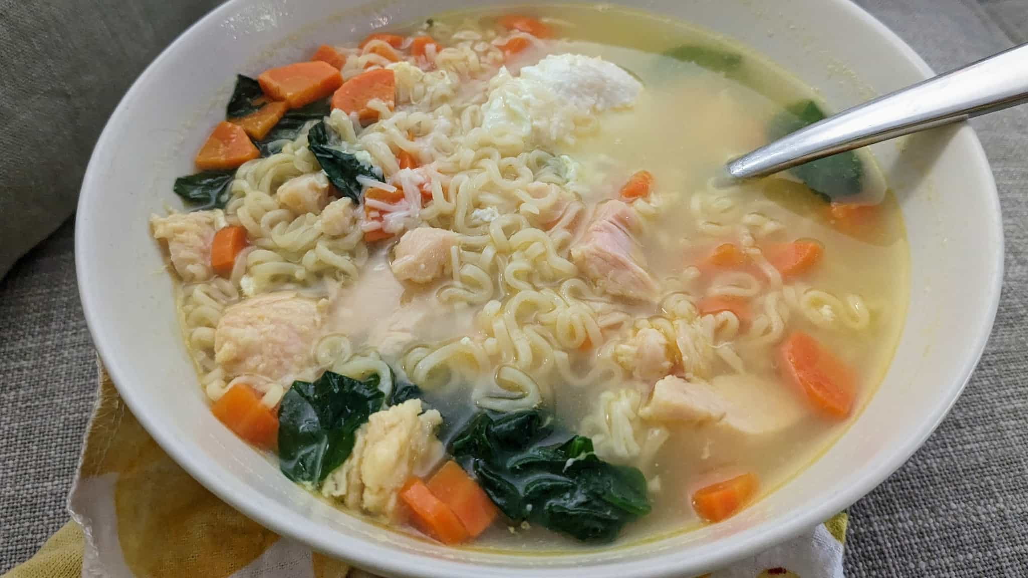 Bowl of noodles, spinach, carrots, chicken, and egg.