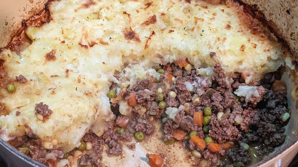Pot with ground meat and veggies topped with mashed potatoes.