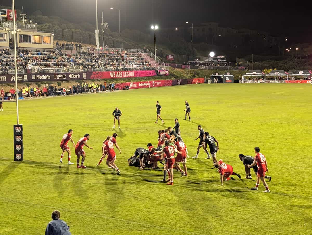 Rugby players in a pile battling as one team is just a few feet from the goal line.