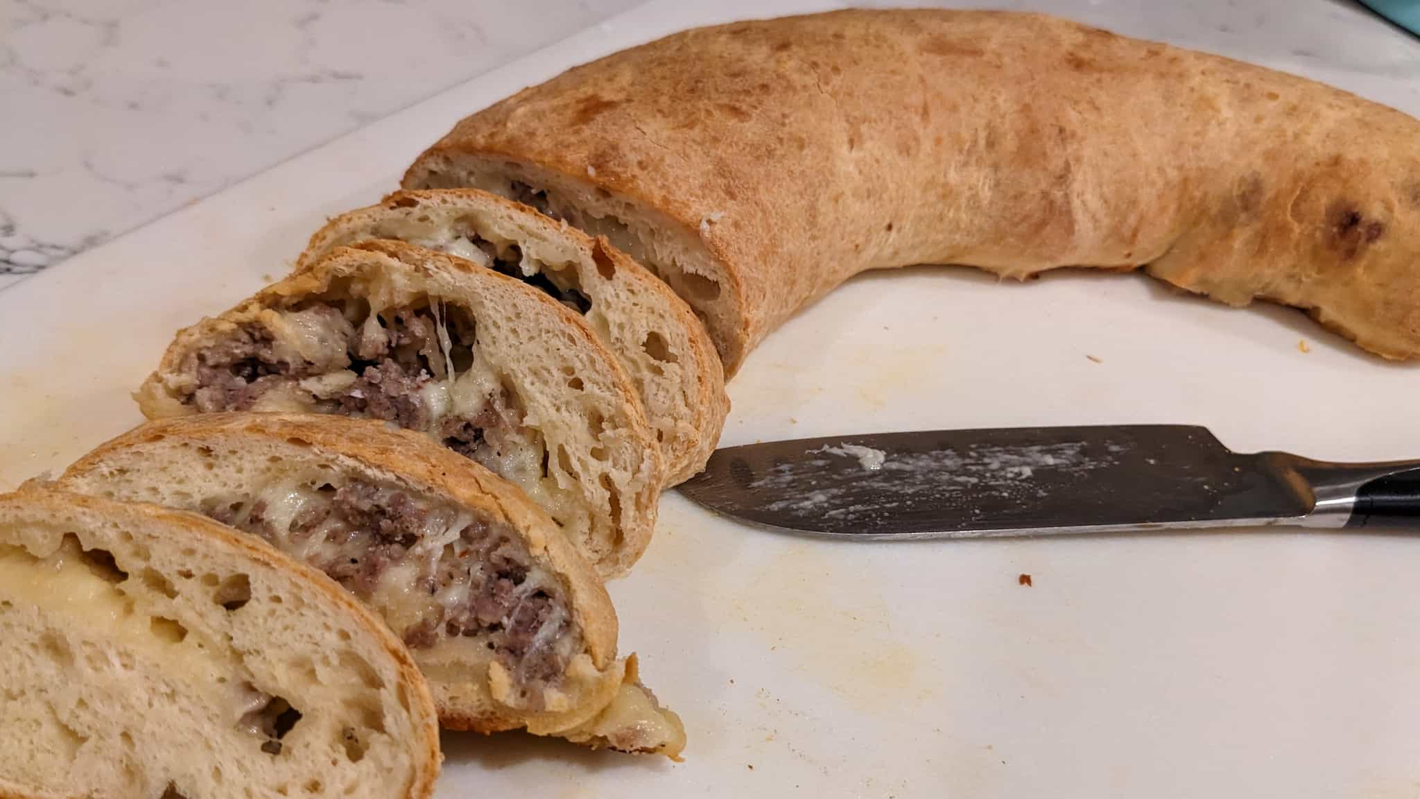 long bread loaf cut open to reveal sausage and cheese inside